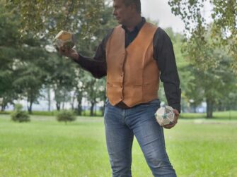 This photo shows the leather waistcoat on the front side. Customer, wearing the vest, stands casually under a birch tree.