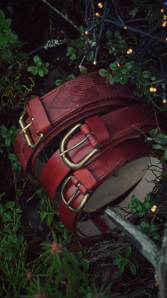 Three darker mahogany tone belts in the midst of dark green forest plants. There are few little sparkling lights on the right top corner.