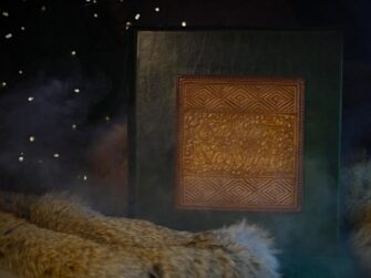 Green photo album is set onto fur and surrounded with a this magical smoke. It has a light brown application on the front cover.