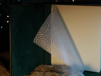 Green photo album is set onto fur and the front cover is opened. The endpapers are made of thin japanese paper.