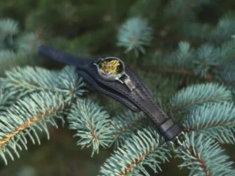 Bracelet is laid onto fir tree branch. The photo demonstrates how the pendant is attached to the topmost strap.