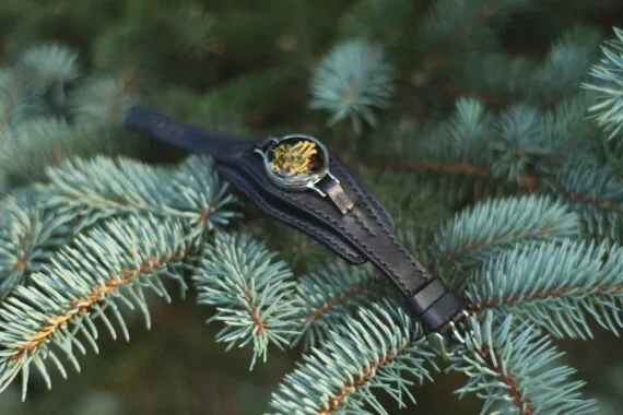 Bracelet is laid onto fir tree branch. The photo demonstrates how the pendant is attached to the topmost strap.