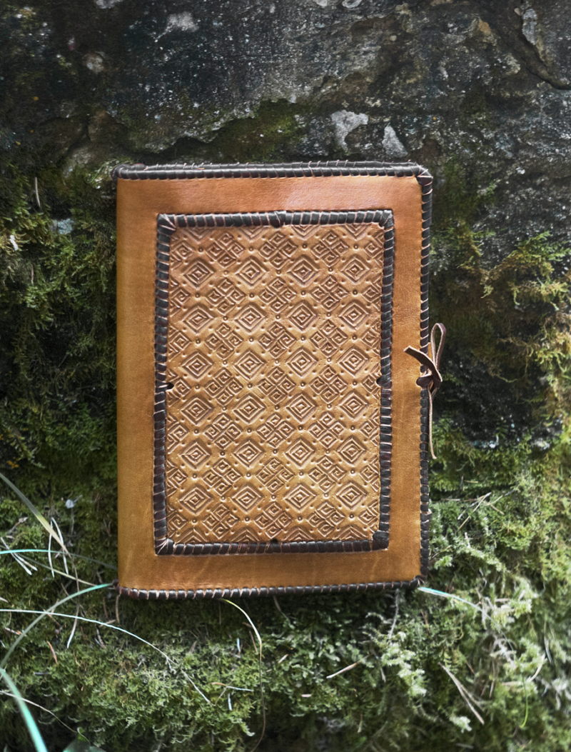 Laced leather notebook covers with hand carved pattern.