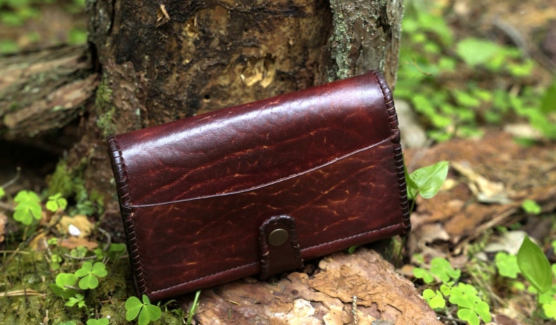 Large leather wallet for women in mahogany with laced edges.