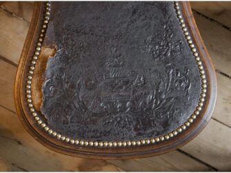This photo is of the antique chair with old leather covers still attached to it. The leather seems quite brittle, is torn and missing pieces.