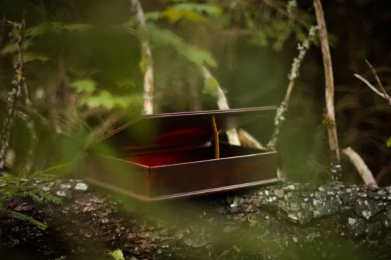 Leather box is set onto the fallen tree trunk. The lid is slightly open and supported by a small stick. Photo shows the overall measurements and look of the box. The bottom and the lid are slightly larger than the middle part of the box, providing a pleasant sight. Wait, there is ... something glowing red inside the box...?