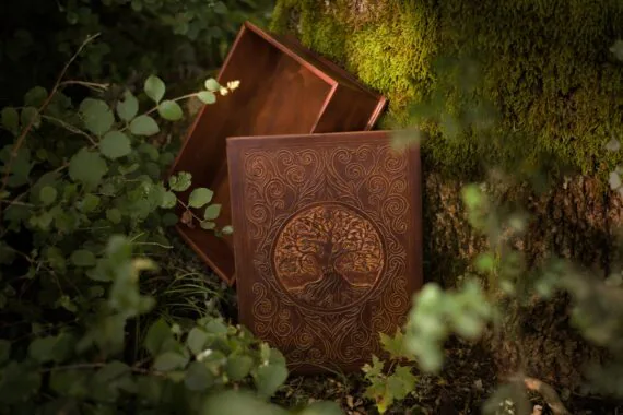 The lid of the leather box has been lifted off the box and set standing besides the box. This photo showcases the beauty of the carved lid as well allows to take a peek to the inside of the box - it is covered evenly with leather outside and inside.