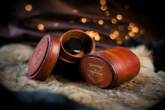 Brown oval shaped leather boxes. One of the boxes is opened and a watch is visible from the inside. The covers of the boxes are decorated by the watchmakers logos.