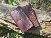 Nahast kaarditasku ja komplekti kuuluv rahakott on kaunistatud nahale voolitud vöökirja mustri ja omaniku initsiaalidega.